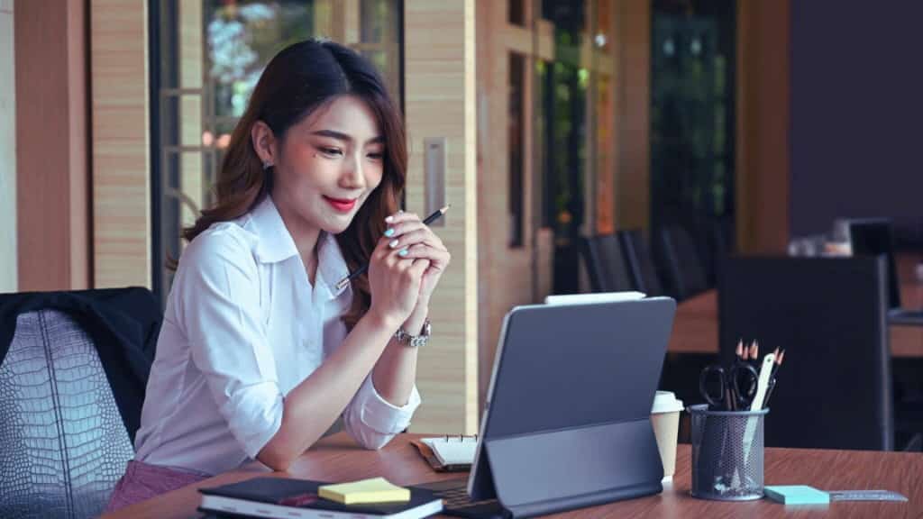 Business Woman Looking Pleased Reading Mobile Tablet at Desk